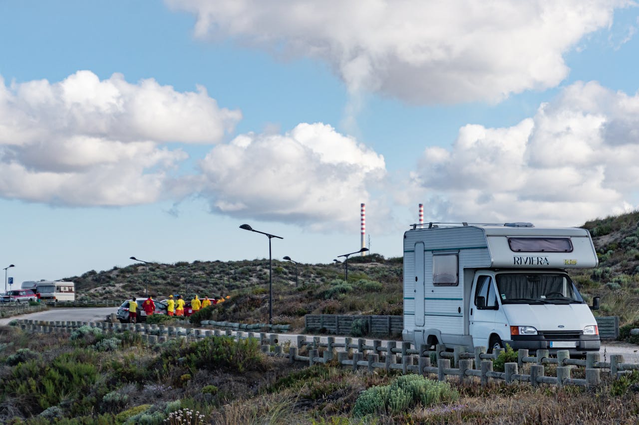 Campervan parked in Portugals scenic landscape under a bright blue sky with fluffy clouds.